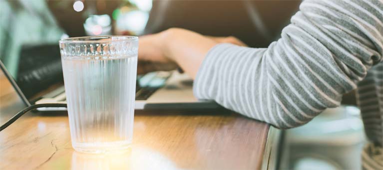 Woman at desk with a glass of water