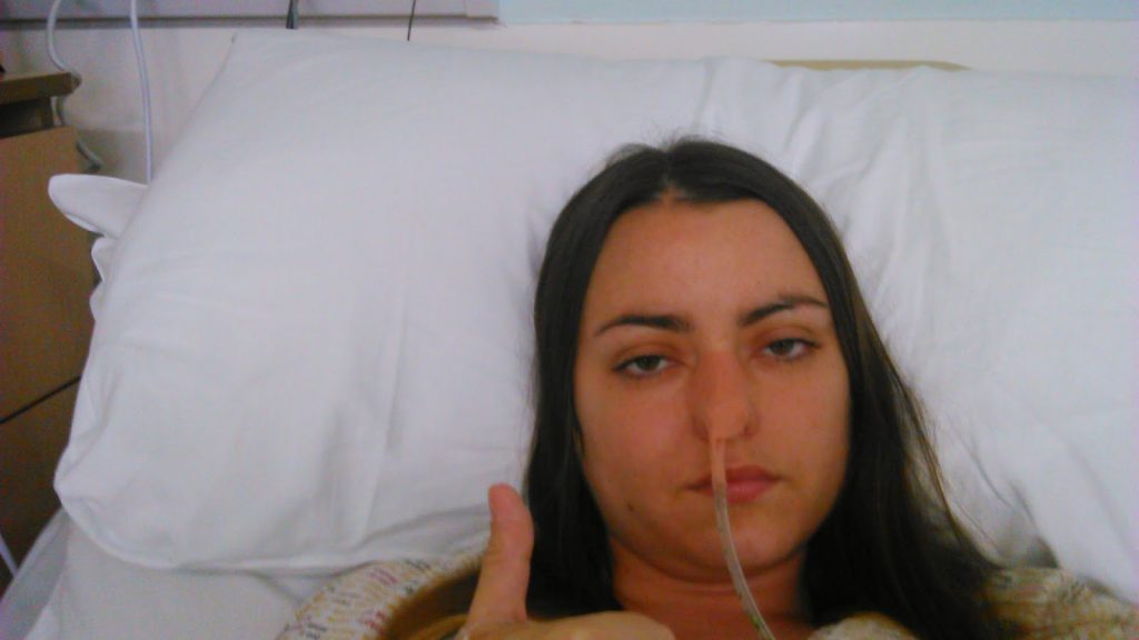 Sahara Fleetwood-Beresford after her stoma surgery. In a hospital bed showing thumbs up
