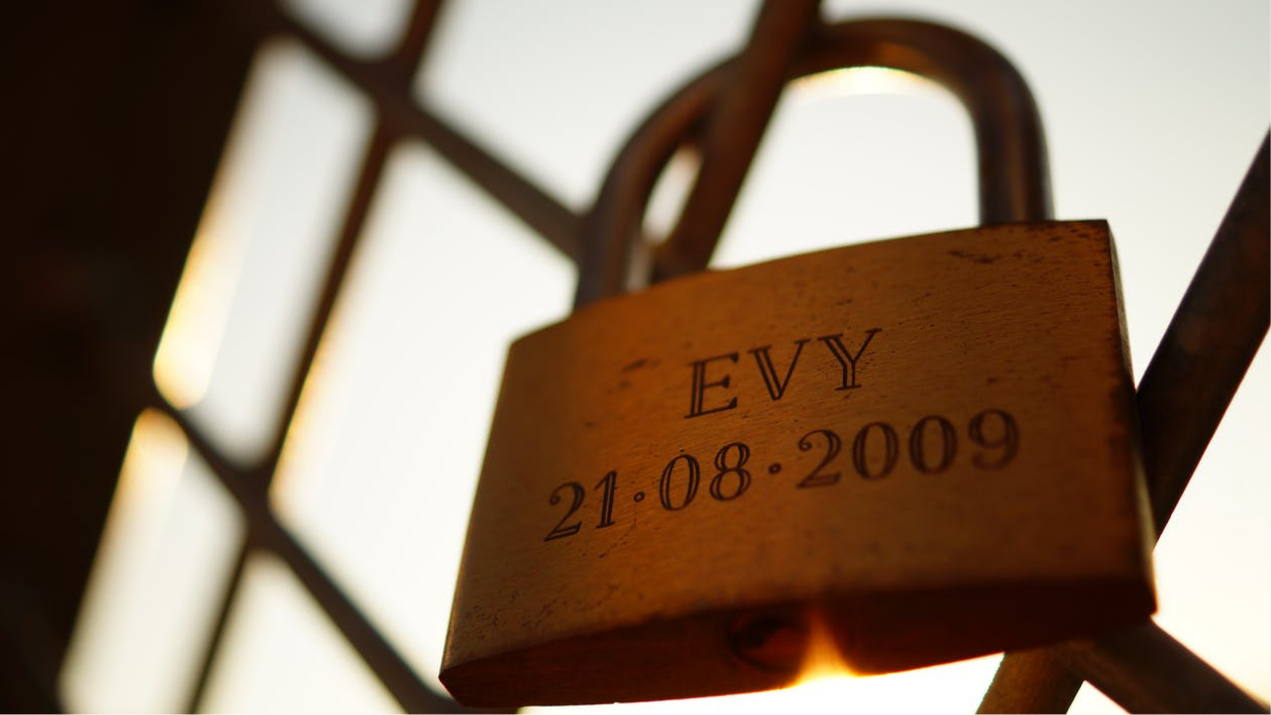 Gold padlock with name Evy and date 21-08-2009 attached to a metal bridge demonstrating union with your stoma