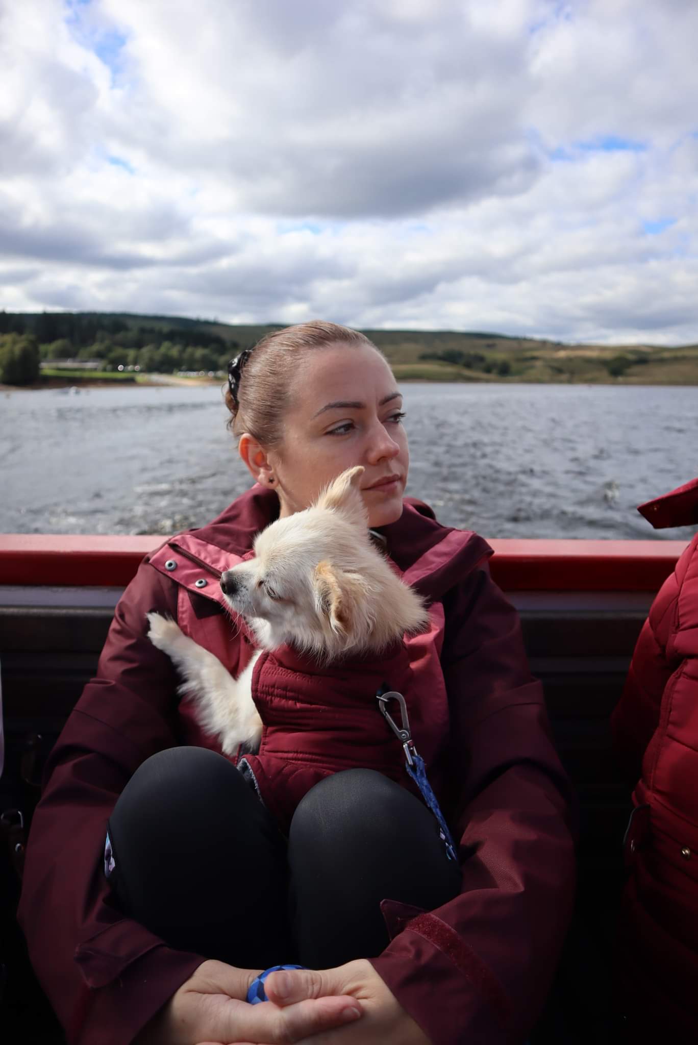 Sahara with her little dog, wrapped up sitting in a small boat on a calm sea