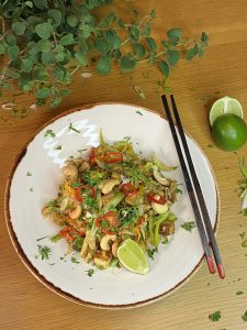 Tofu, cashew and egg fried rice, served on a white dish with chop sticks to the side and garnished with lime