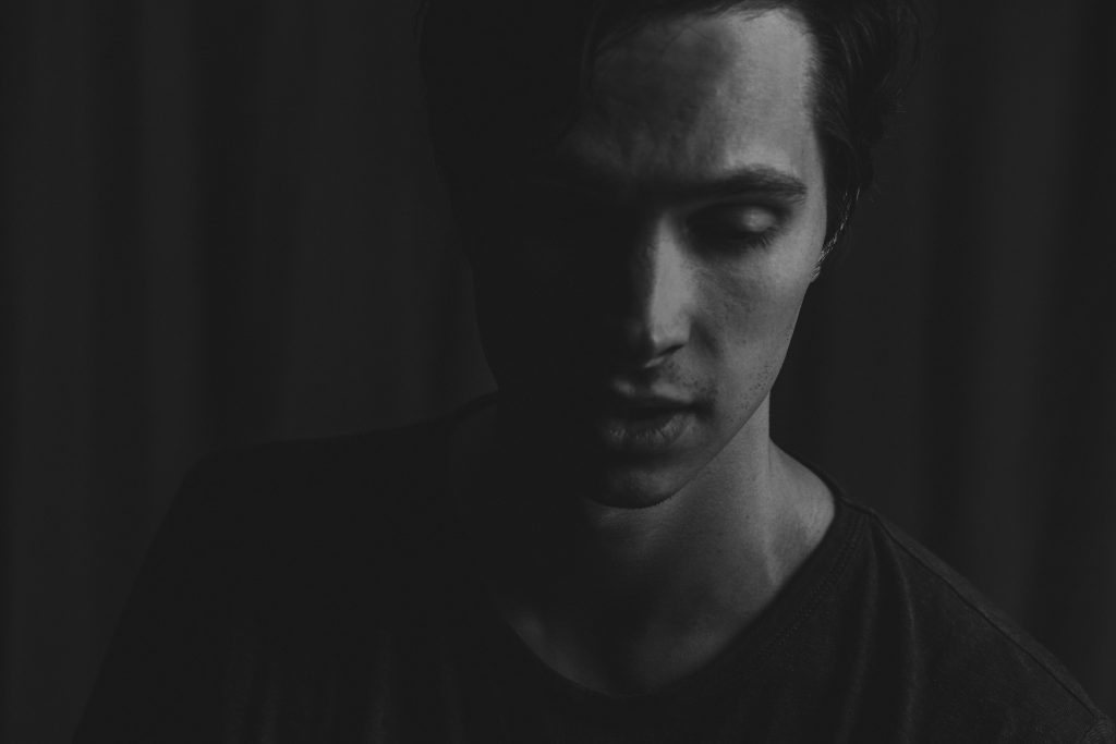 black and white photograph of a man looking pensive, eyes to the ground.