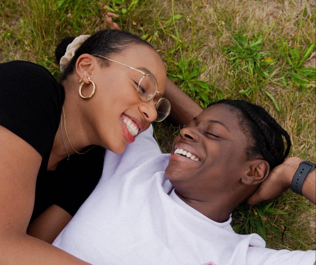 Happy, smiling couple laying down next to each other on the grass, summertime