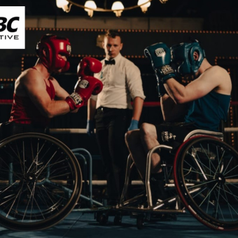 A competitive adaptive boxing match with one boxer in red and the other in blue with a referee in the background