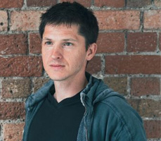 Wayne standing against a red brick wall