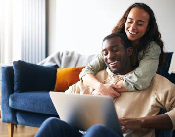 Woman hugging a man using a laptop