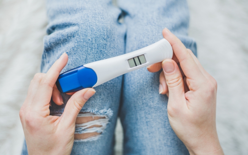 woman holding a pregnancy test kit with positive result on her lap